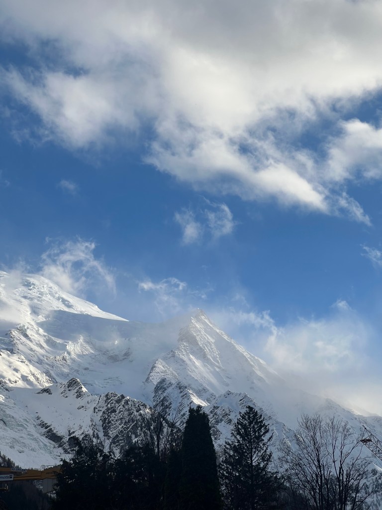 Mont Blanc massif wrapped in clouds above the trees, Chamonix - photo by Sakine Gulec